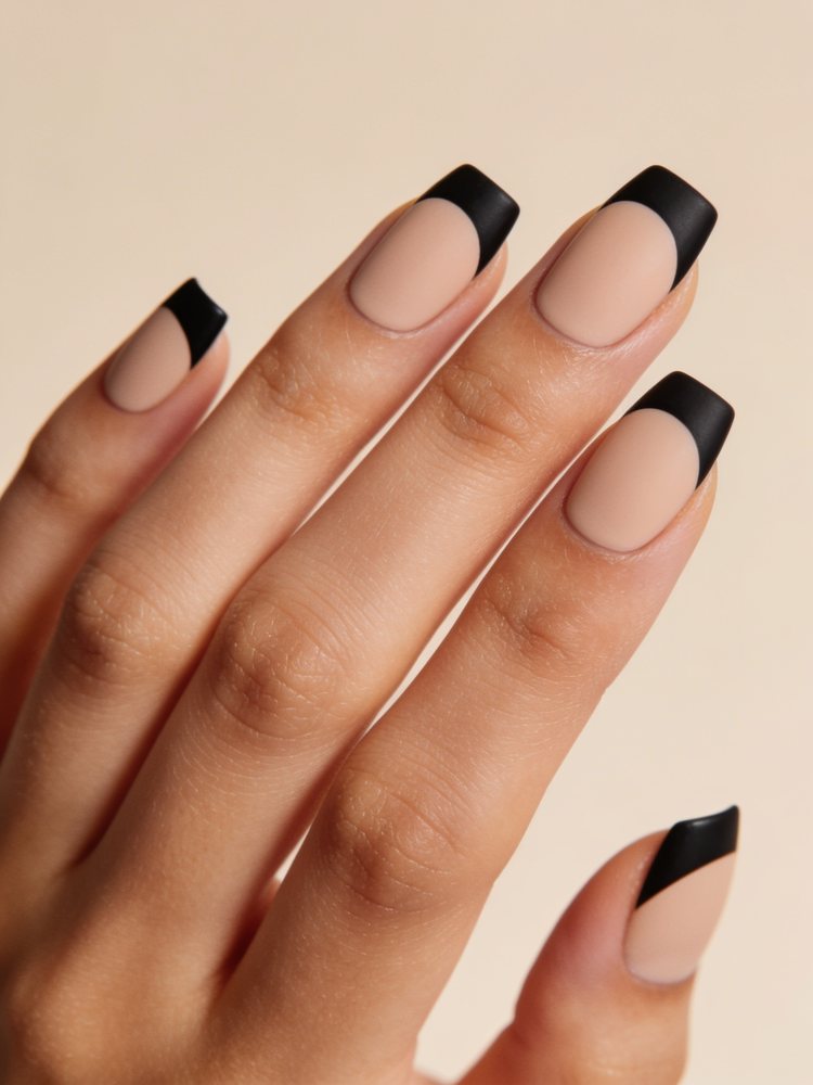 Short squoval nails in nude with matte black French tips